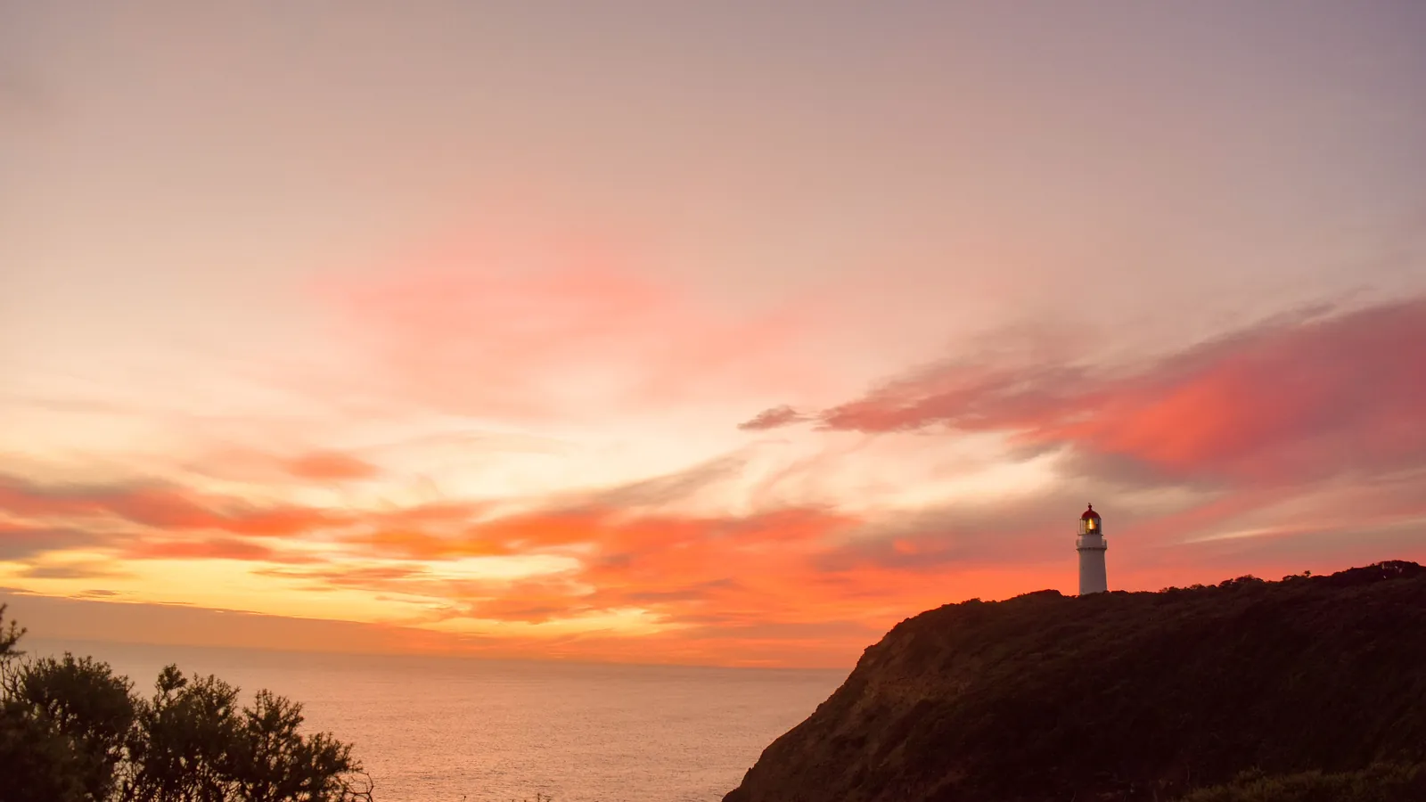 Cape Schanck Lighthouse silhouetted on the headland under a pink and orange sunset