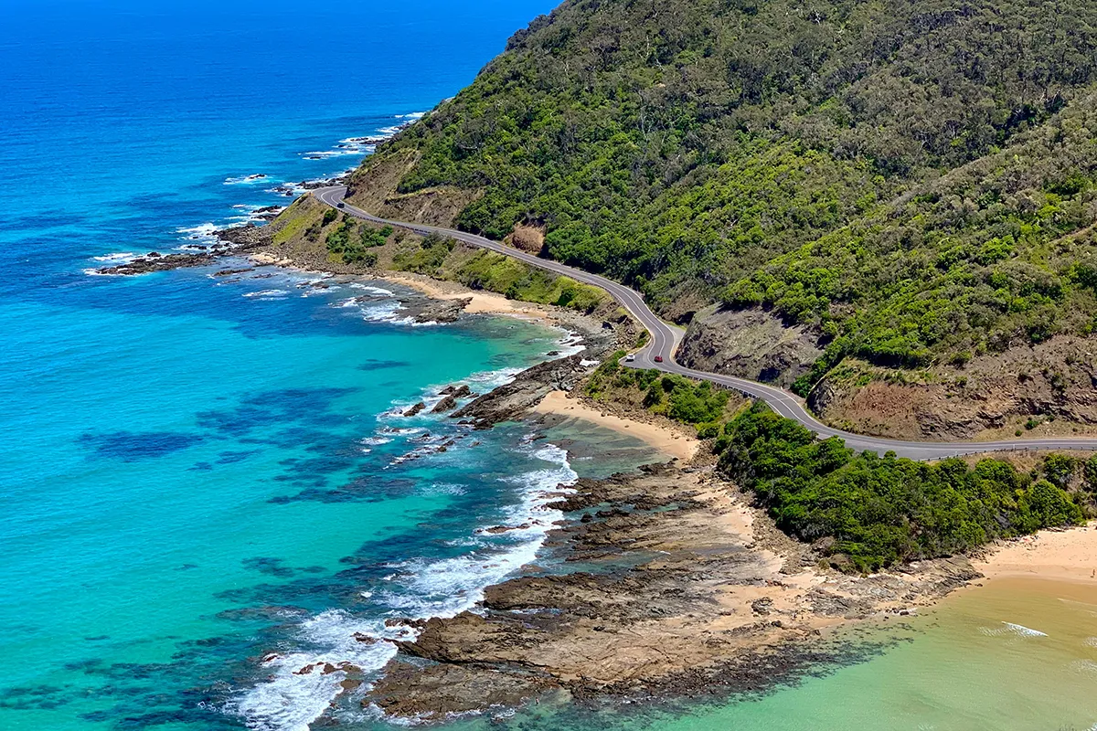 Aerial view of the Great Ocean Road winding along the coast near Lorne with turquoise water below