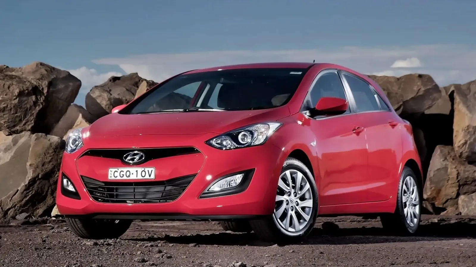 hyundai-i30-active1-red Red Hyundai i30 GD hatchback parked in front of large boulders, front three-quarter view