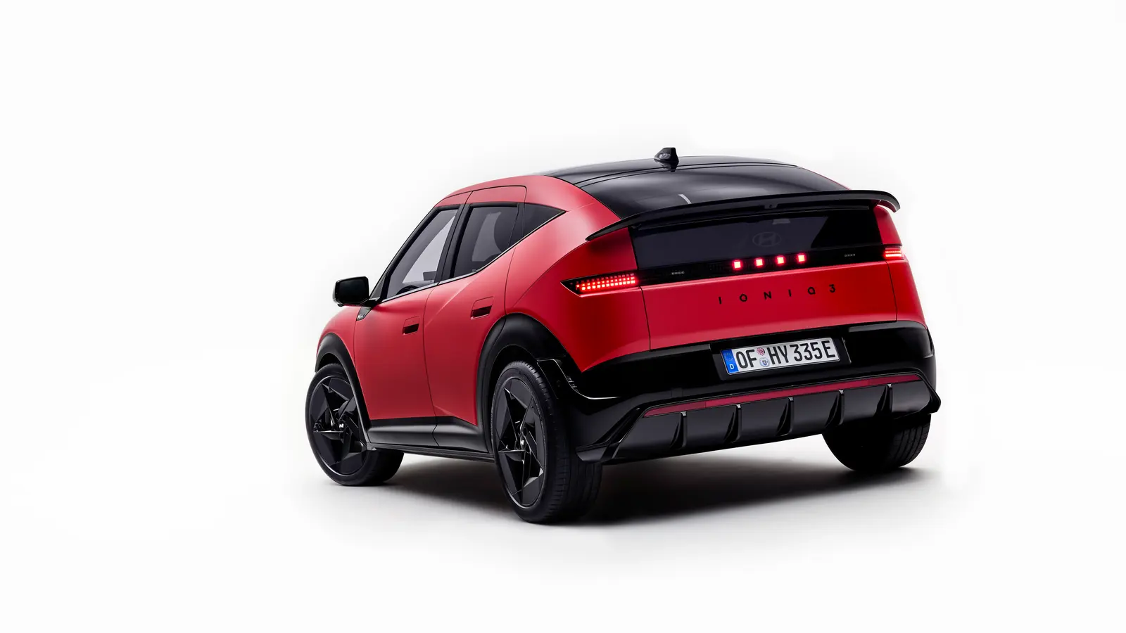 Rear three-quarter view of the Hyundai Ioniq 3 showing its full-width tail light bar and roof spoiler