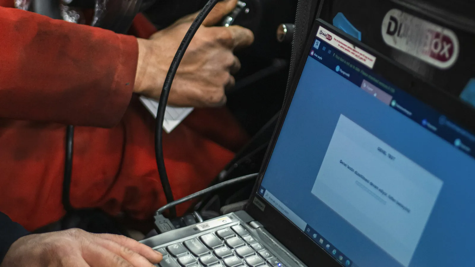 Technician's laptop connected by a diagnostic cable to a car, the kind of setup used for an ECU tune