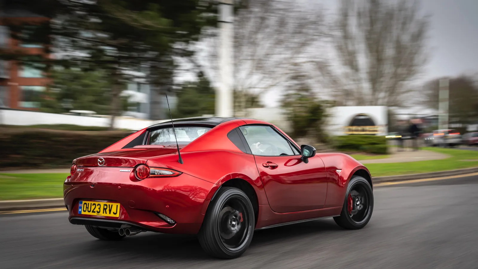 Red Mazda MX-5 RF on the move, rear three-quarter view showing its fastback folding hardtop