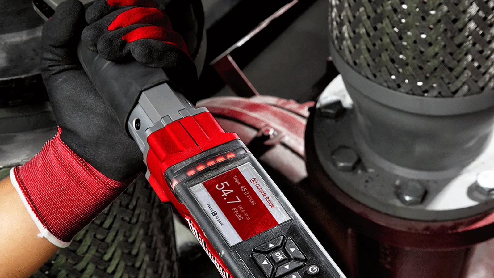 Gloved hands using a Milwaukee M12 FUEL digital torque wrench with its display showing the live torque reading