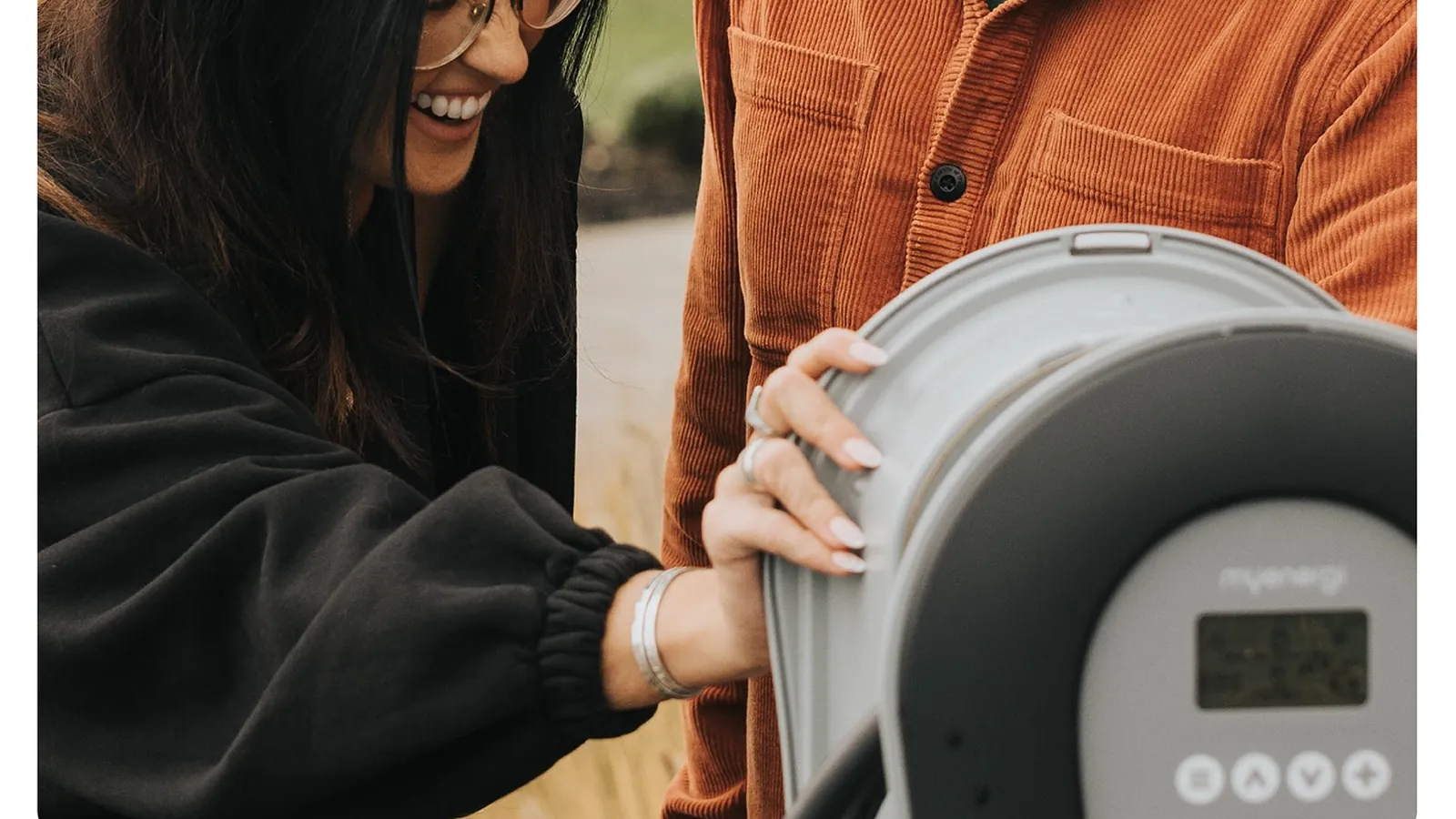 Couple unboxing a myenergi zappi solar EV charger showing its display and control buttons