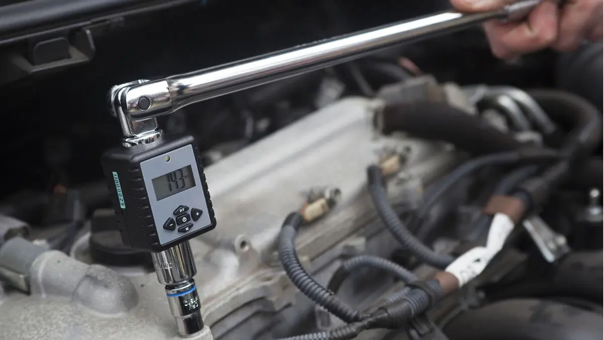 ToolPRO digital torque adaptor fitted between a long ratchet handle and socket on an engine bolt in a car engine bay