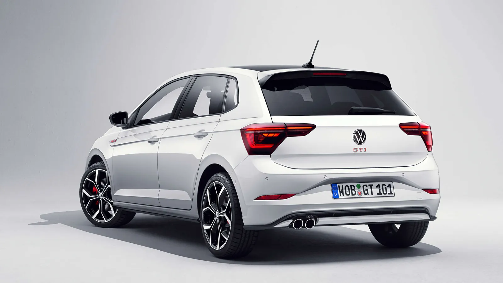 White Volkswagen Polo GTI hatchback in a studio, rear three-quarter view showing the GTI badge and twin exhausts
