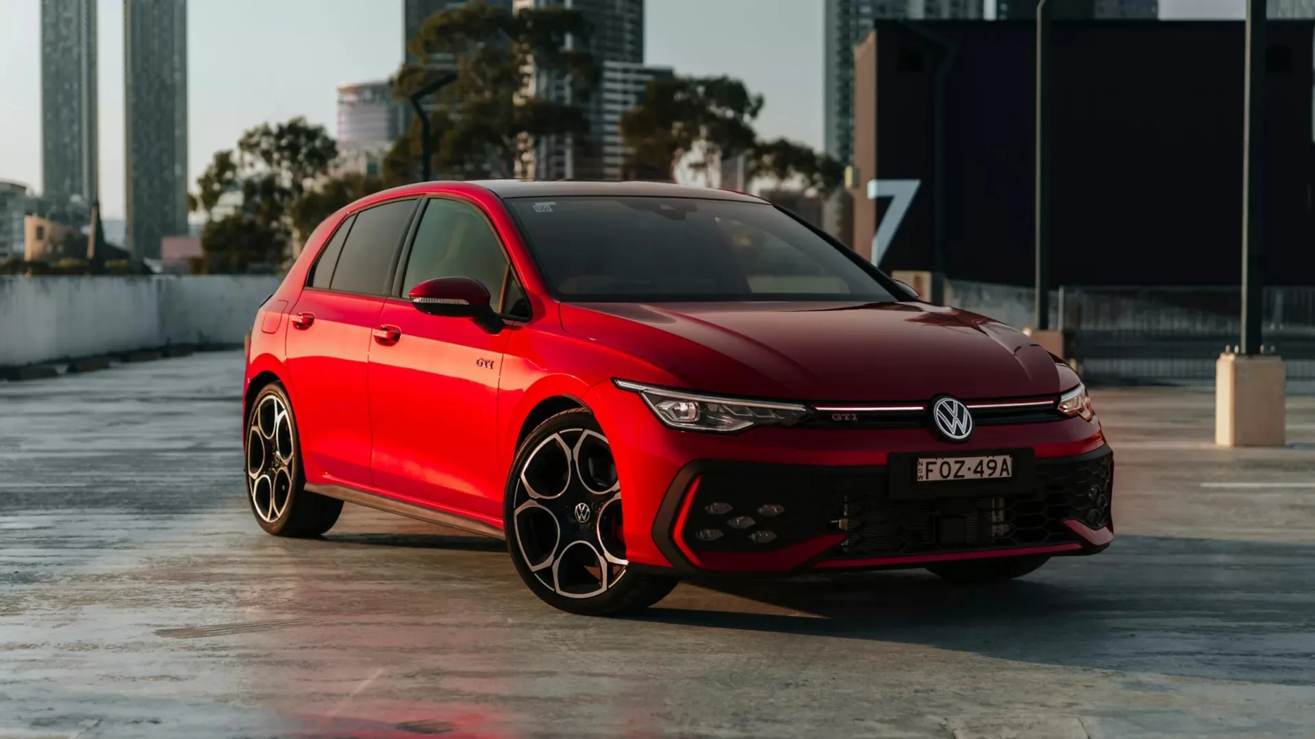 Red 2026 Volkswagen Golf GTI hatchback with NSW plates parked on a city rooftop car park