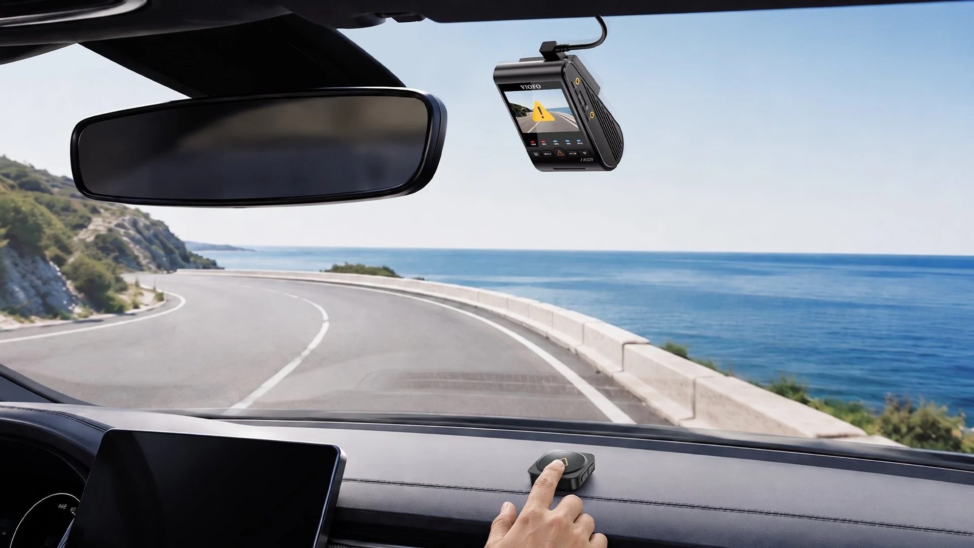 VIOFO A329S dash cam behind the mirror VIOFO A329S dash cam mounted behind the rear-view mirror, with a coastal road through the windscreen