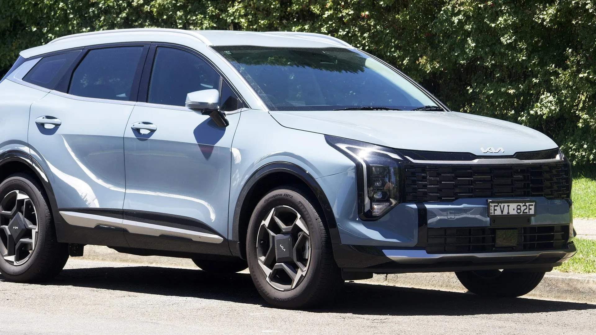 Kia Sportage on an Australian street, best hybrid SUV Australia 2026 Facelifted Kia Sportage SX in light blue parked on a tree-lined street in Bowral, New South Wales