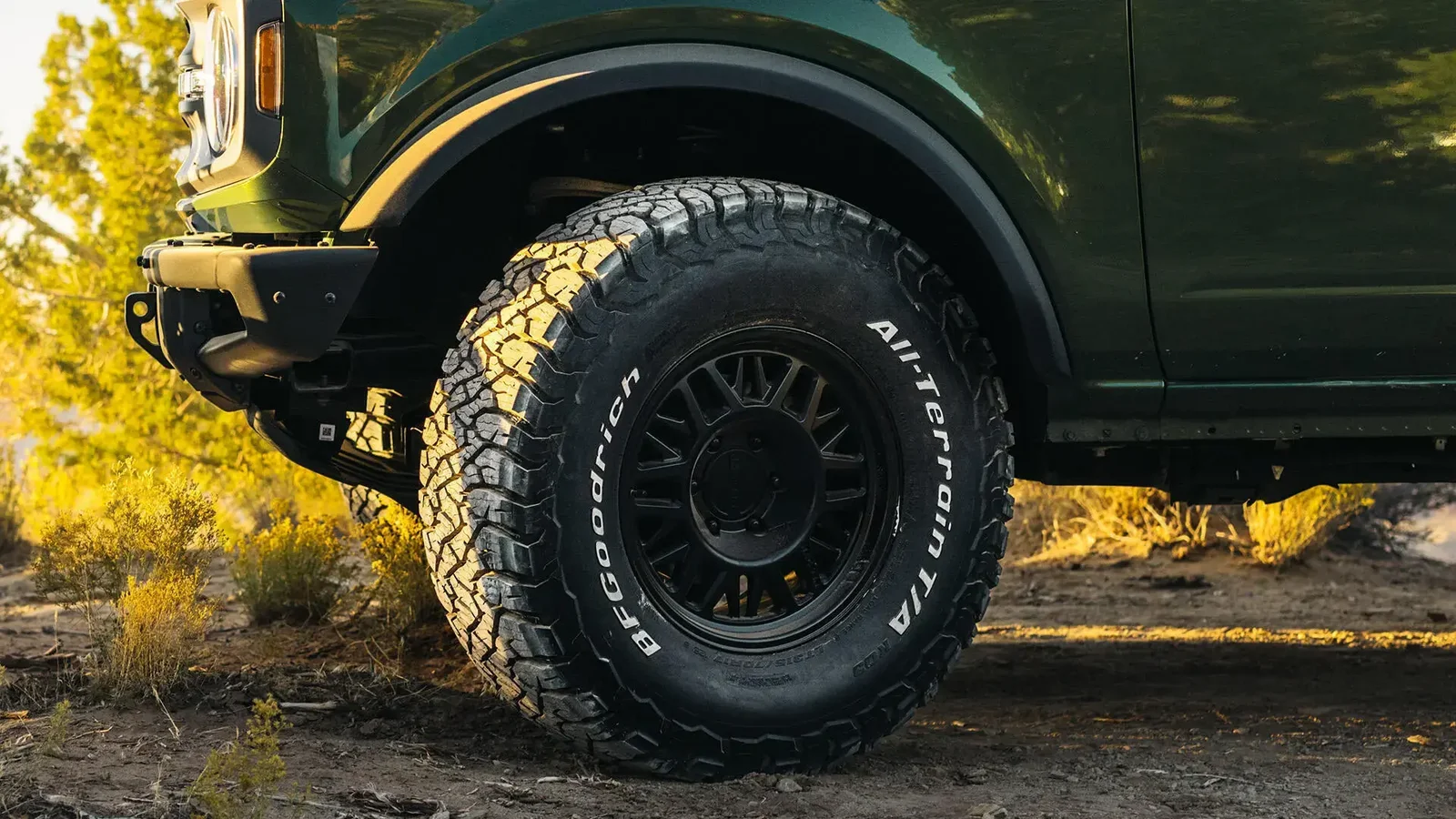BFGoodrich All-Terrain T/A KO3 tyre with raised white lettering fitted to a dark green 4WD on dirt