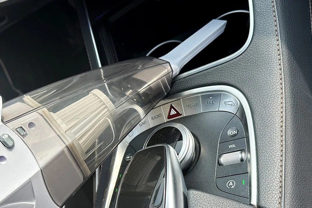 Cabin Crew 12V car vacuum with crevice nozzle cleaning between the centre console buttons and gear selector