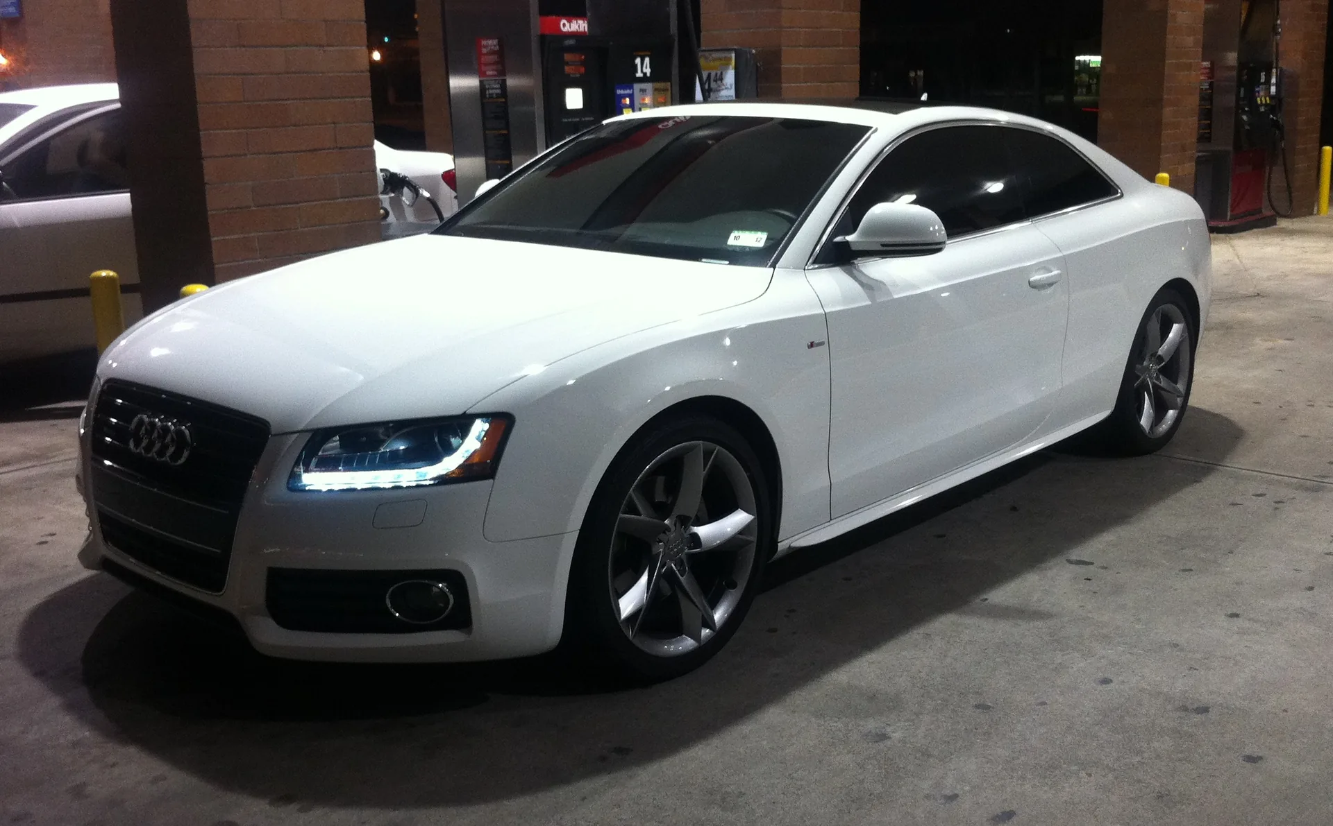 White Audi A5 coupe at a service station with very dark limo-style tint on the front side windows