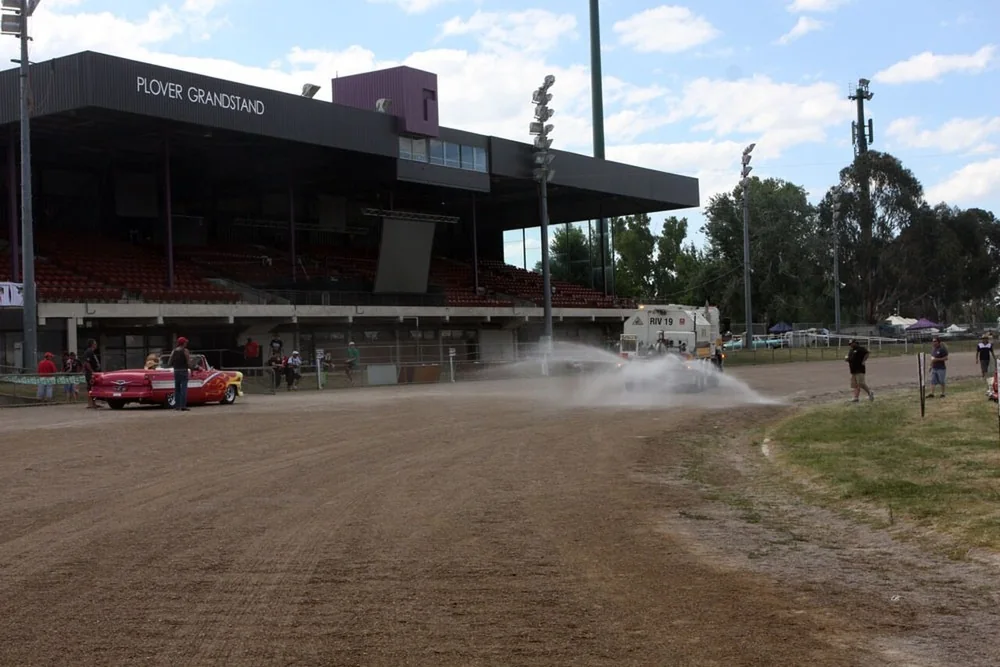 Grandstand and dirt track at Exhibition Park in Canberra during Summernats, with a car kicking up dust