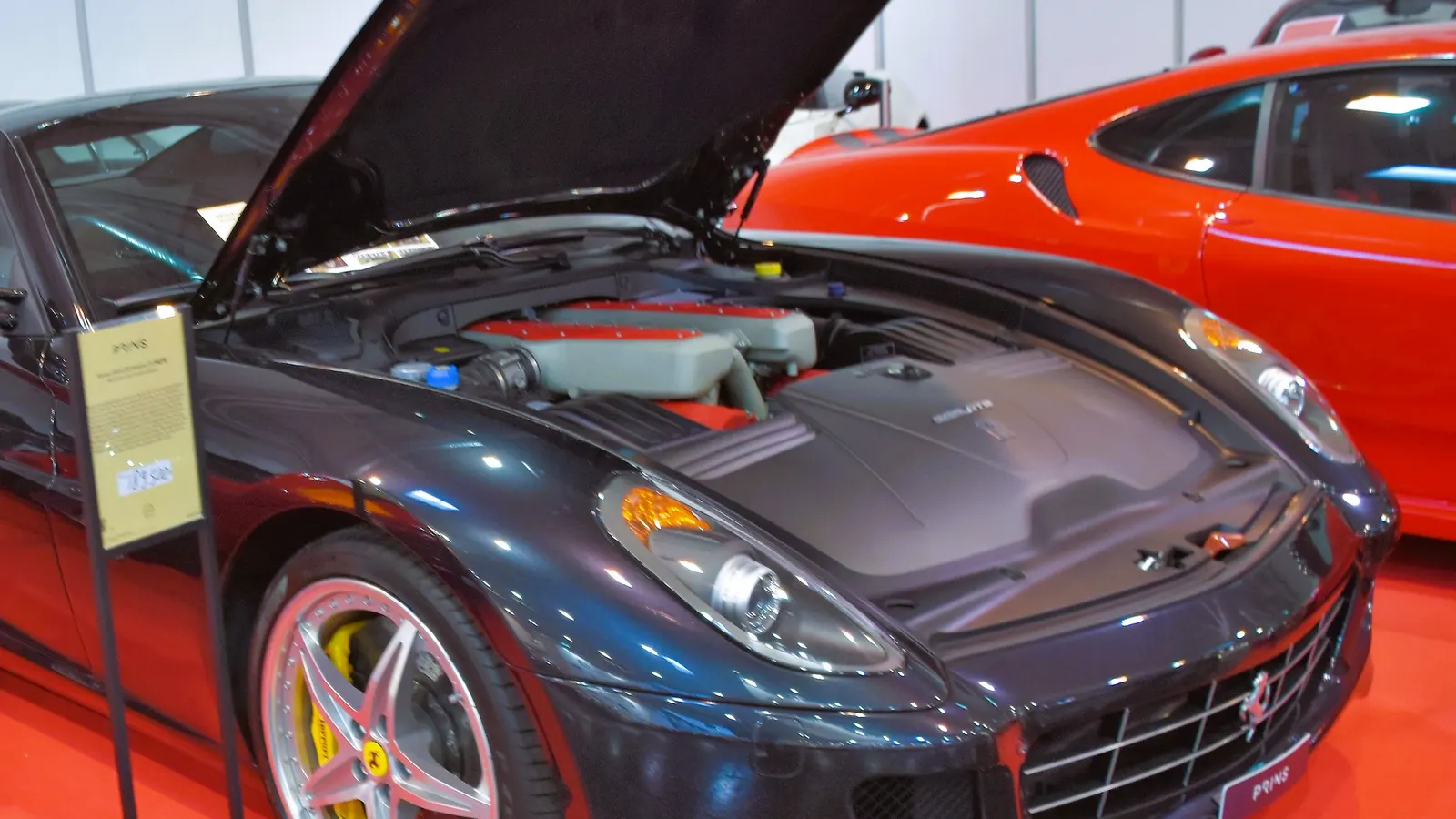 Dark blue Ferrari 599 GTB Fiorano with its bonnet raised, showing the red-topped F140 V12 engine