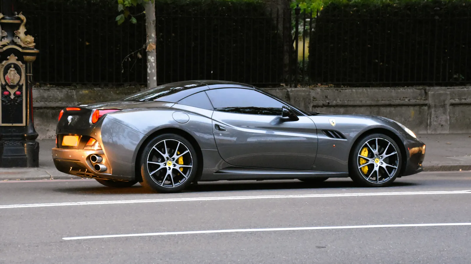 Grey 2009 Ferrari California hardtop convertible in side profile on a London street
