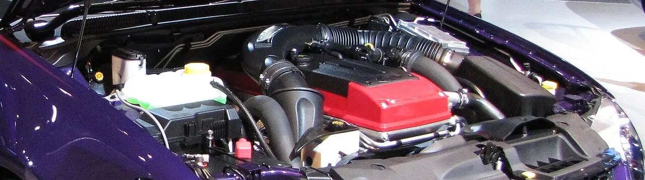 Engine bay of a Ford FG Falcon showing the Barra 4.0-litre turbo six with its red cam cover and intake plumbing