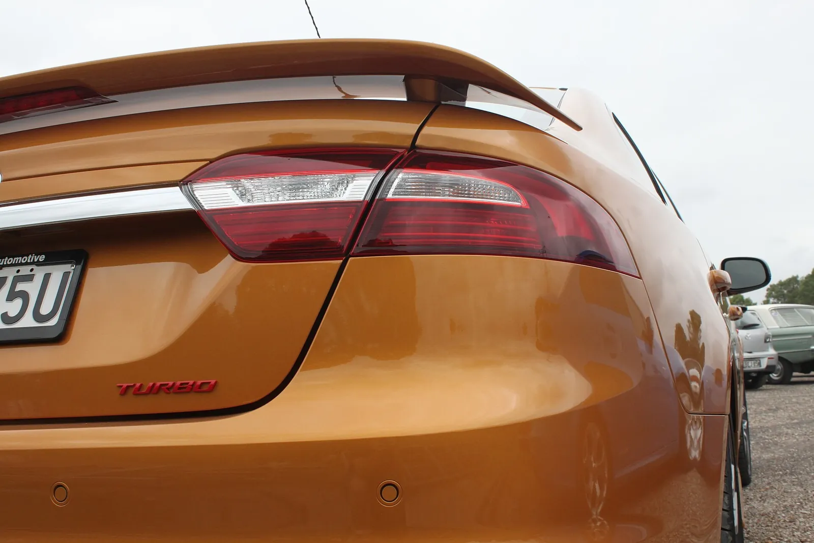 Rear quarter of an orange Ford FG X Falcon XR6 Turbo showing the red Turbo badge and tail-light