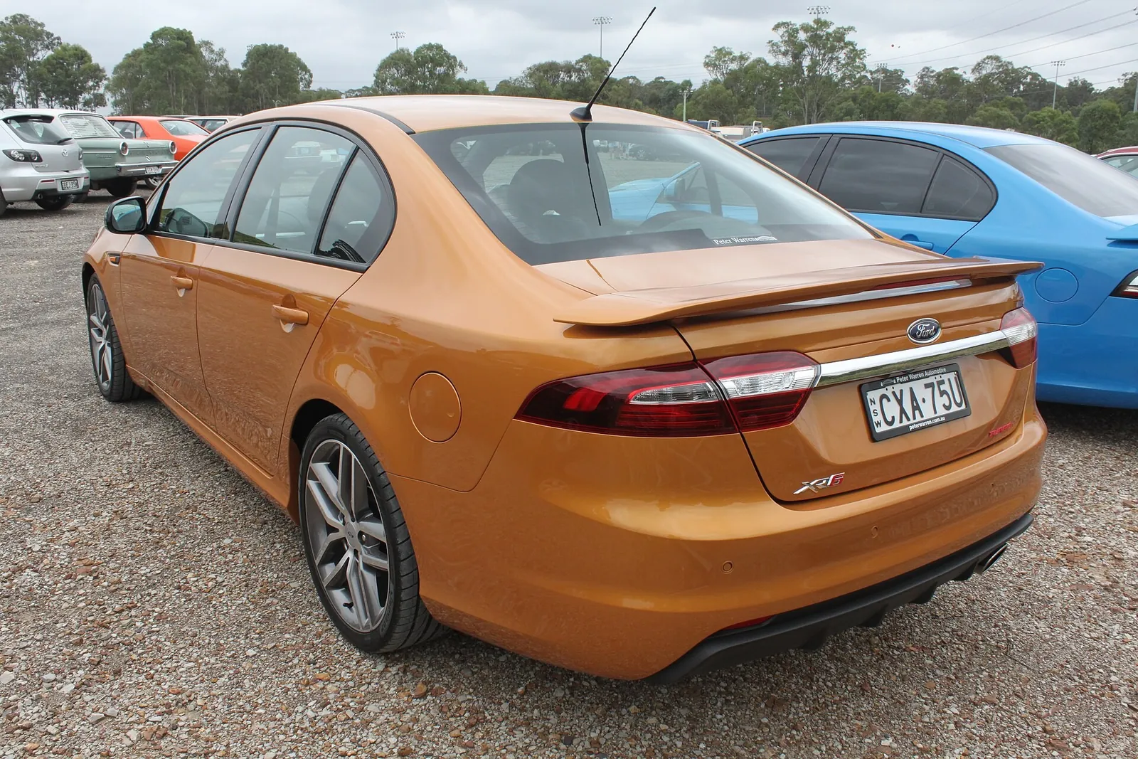 Orange Ford FG X Falcon XR6 Turbo sedan, rear three-quarter view showing the boot spoiler and twin exhausts