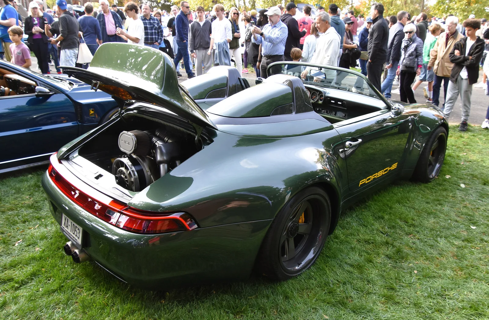 Rear three-quarter of a green Gunther Werks 993 Speedster with the engine lid raised over its air-cooled flat-six