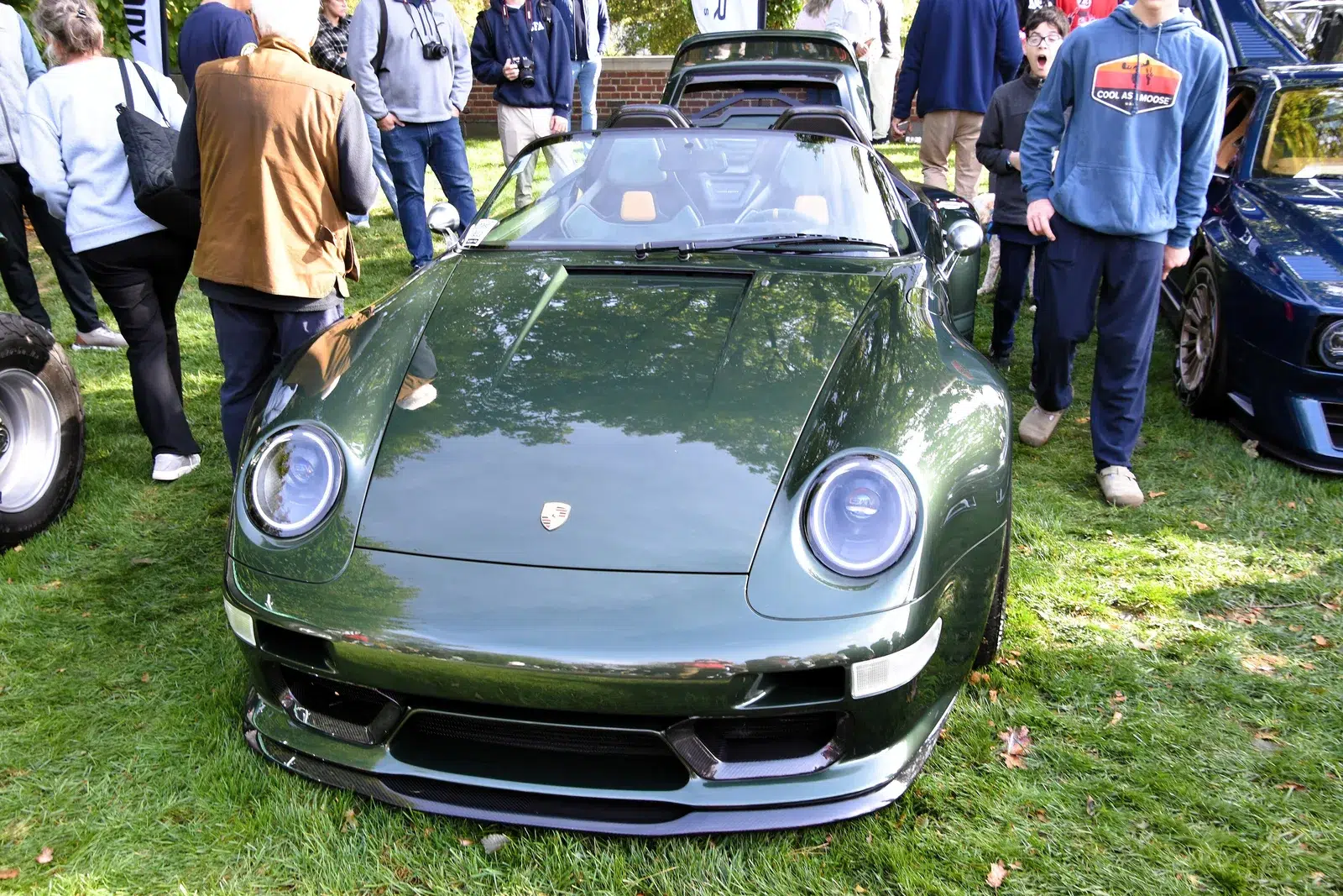 Front view of a green Gunther Werks 993 Speedster showing its LED headlights, carbon splitter and widened front guards