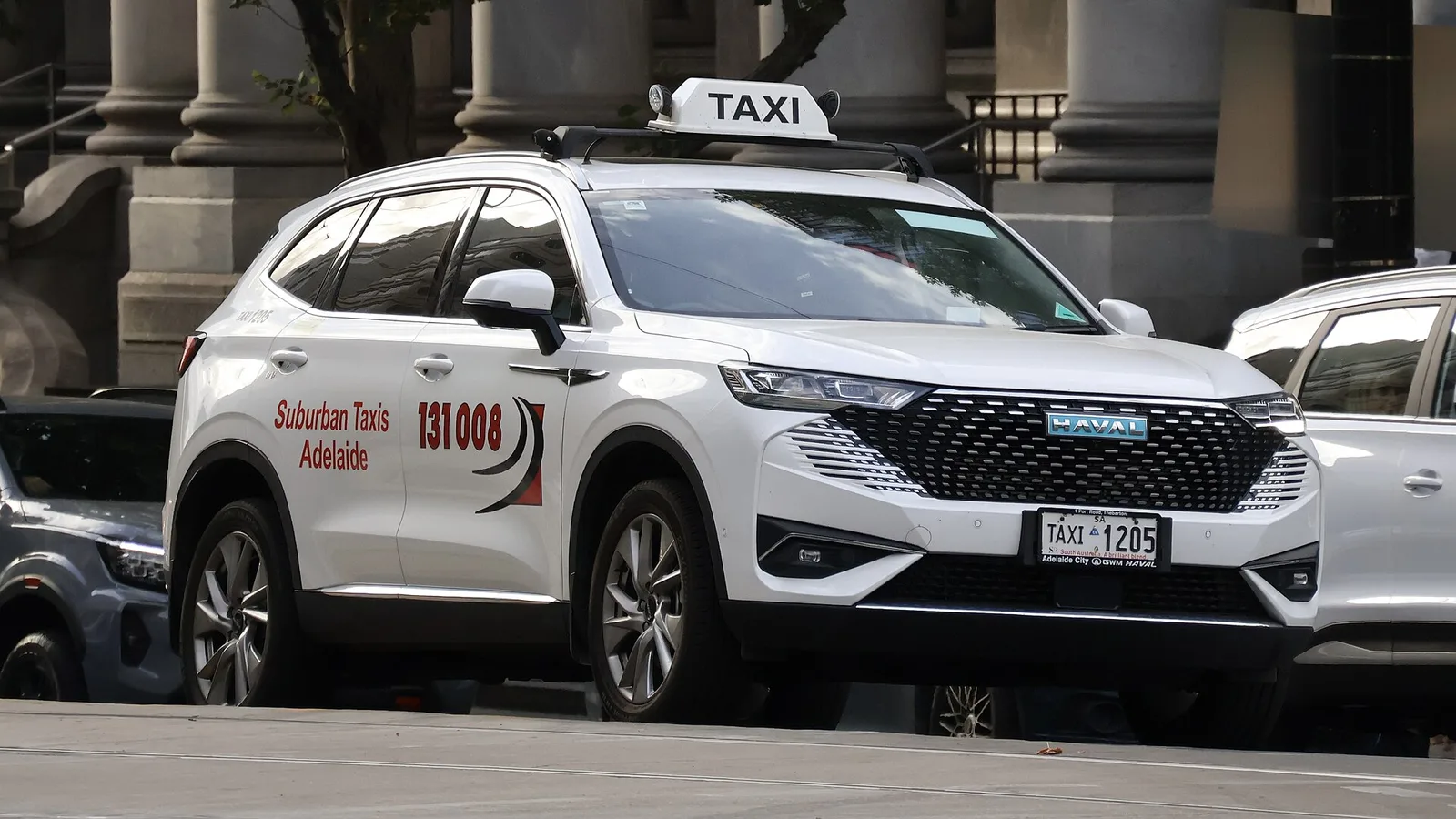 White GWM Haval H6 Hybrid SUV in Suburban Taxis livery parked on a street in Adelaide