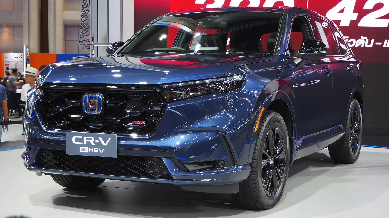 Blue sixth-generation Honda CR-V e:HEV RS on a motor show stand, front three-quarter view