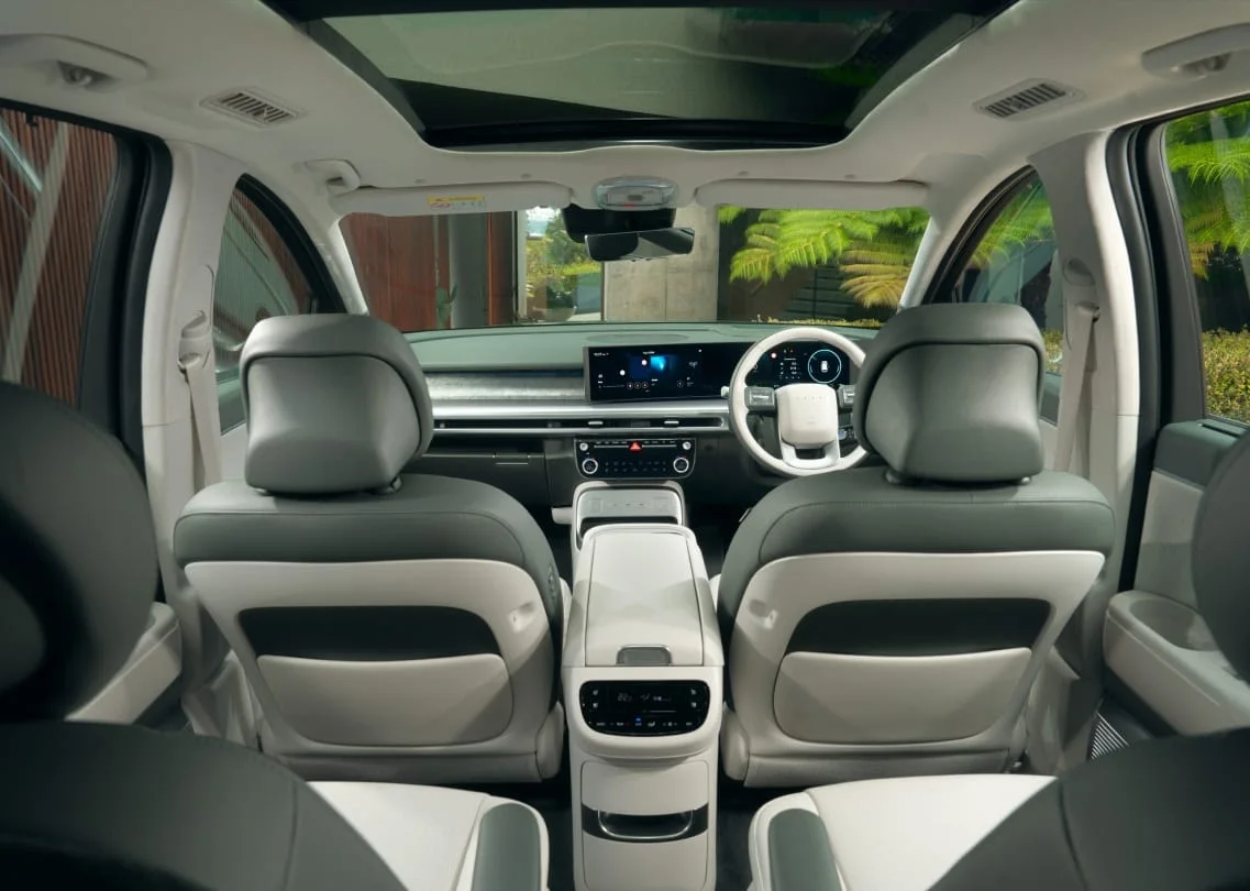 Hyundai Ioniq 9 cabin viewed from the third row showing second-row captain's chairs and dashboard screens