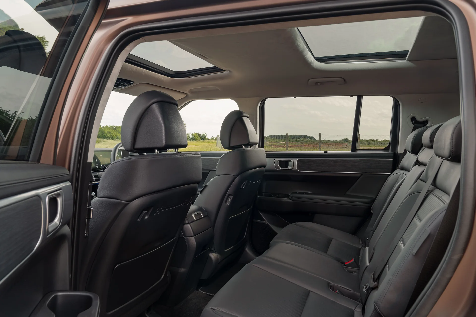Second-row seats of the Hyundai Santa Fe seen through the open rear door, with panoramic sunroof above