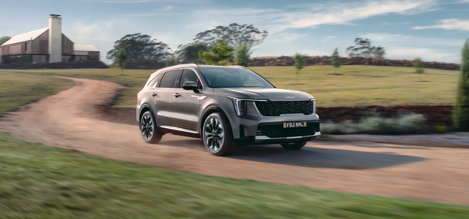 2026 Kia Sorento seven-seat SUV in grey driving along a dirt farm road with Australian plates