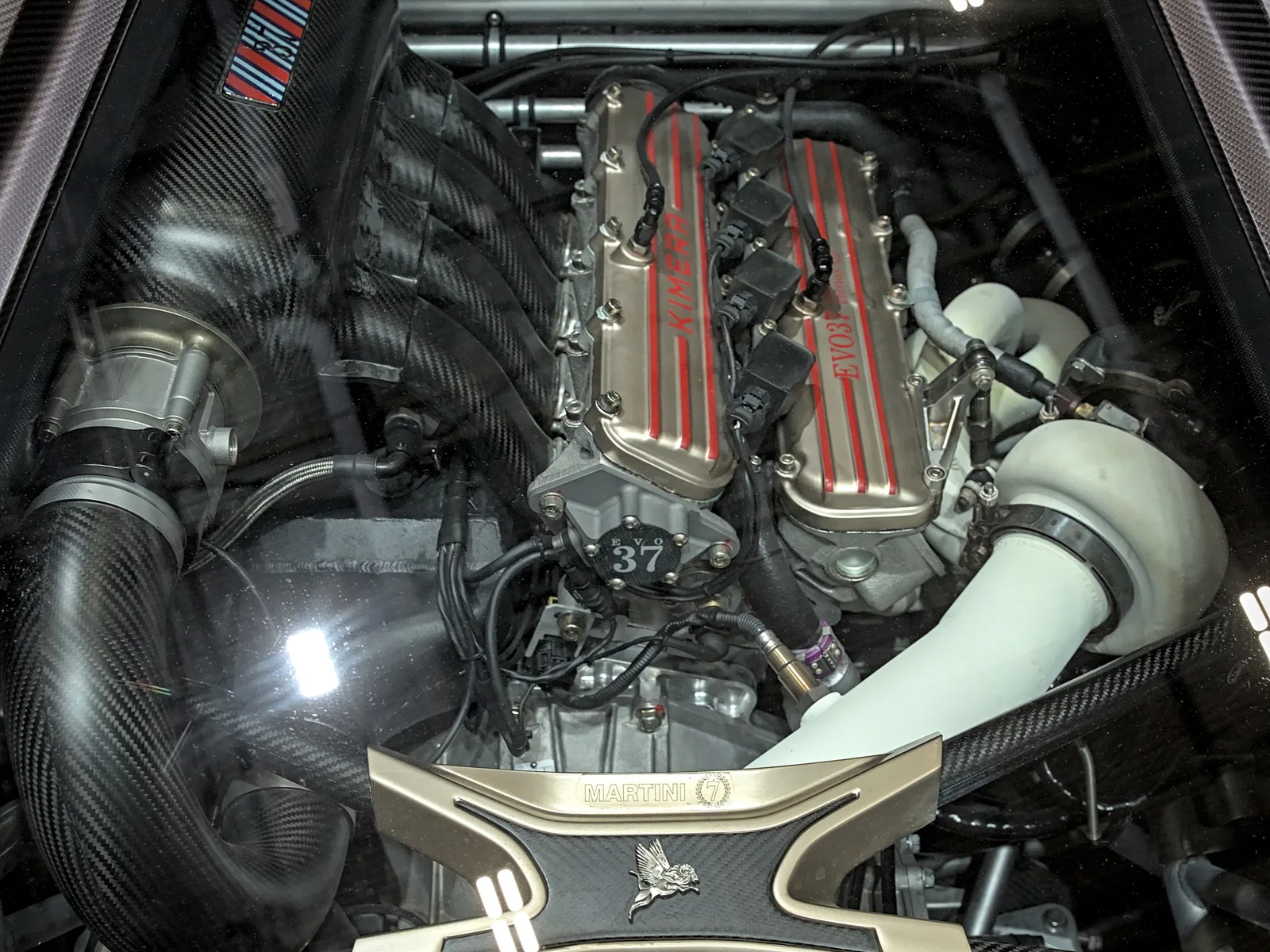Engine bay of a Kimera EVO37 Martini 7 showing the 2.1-litre four, carbon intake and turbo plumbing under glass