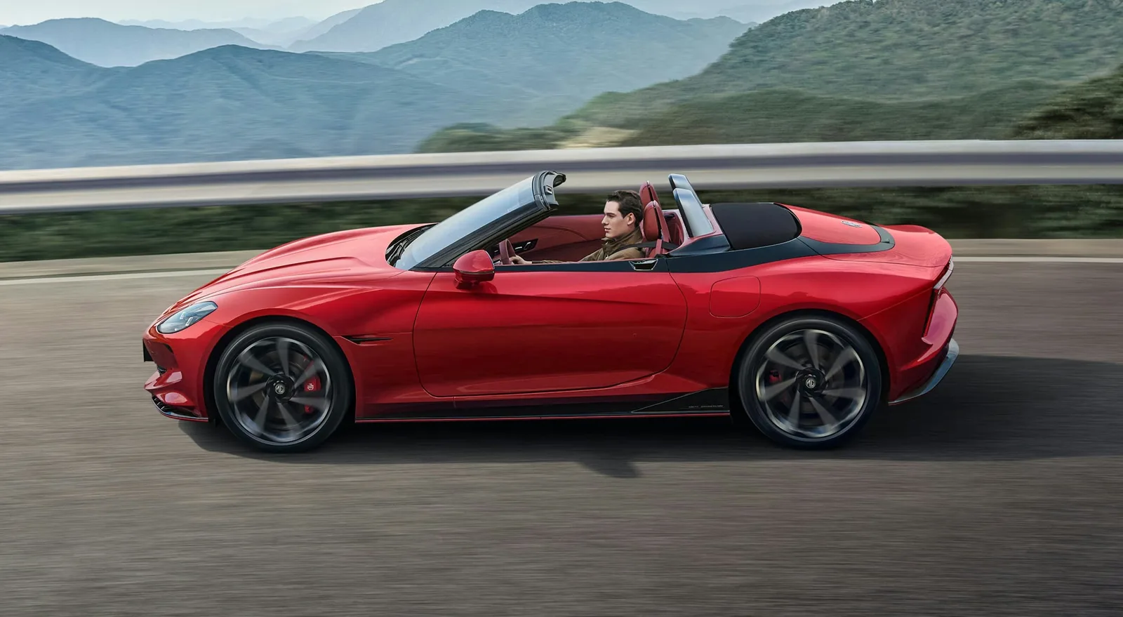 Red MG Cyberster driving roof down on a mountain road, full side profile with doors closed