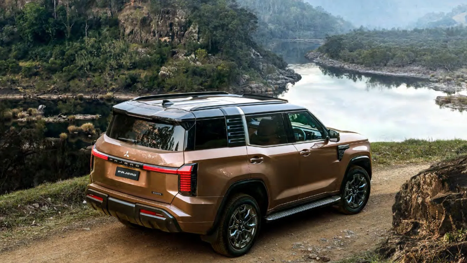Copper 2027 Mitsubishi Pajero GSR with black roof parked above a river on a dirt track, rear three-quarter view