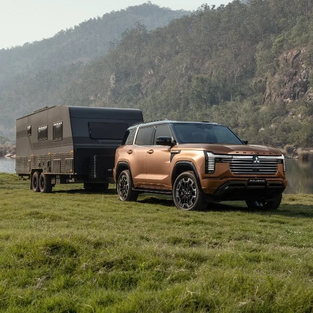 Copper 2027 Mitsubishi Pajero towing an off-road caravan across grass
