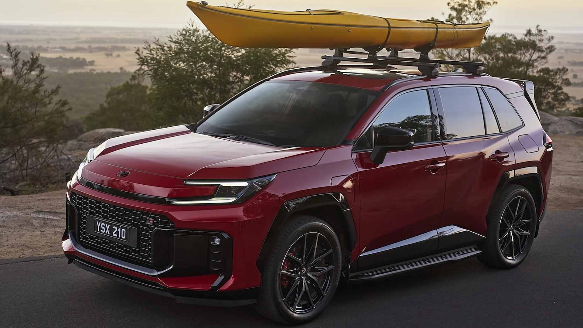 2026 Toyota RAV4 Red 2026 Toyota RAV4 with a yellow kayak on its roof racks, parked at a lookout at sunset