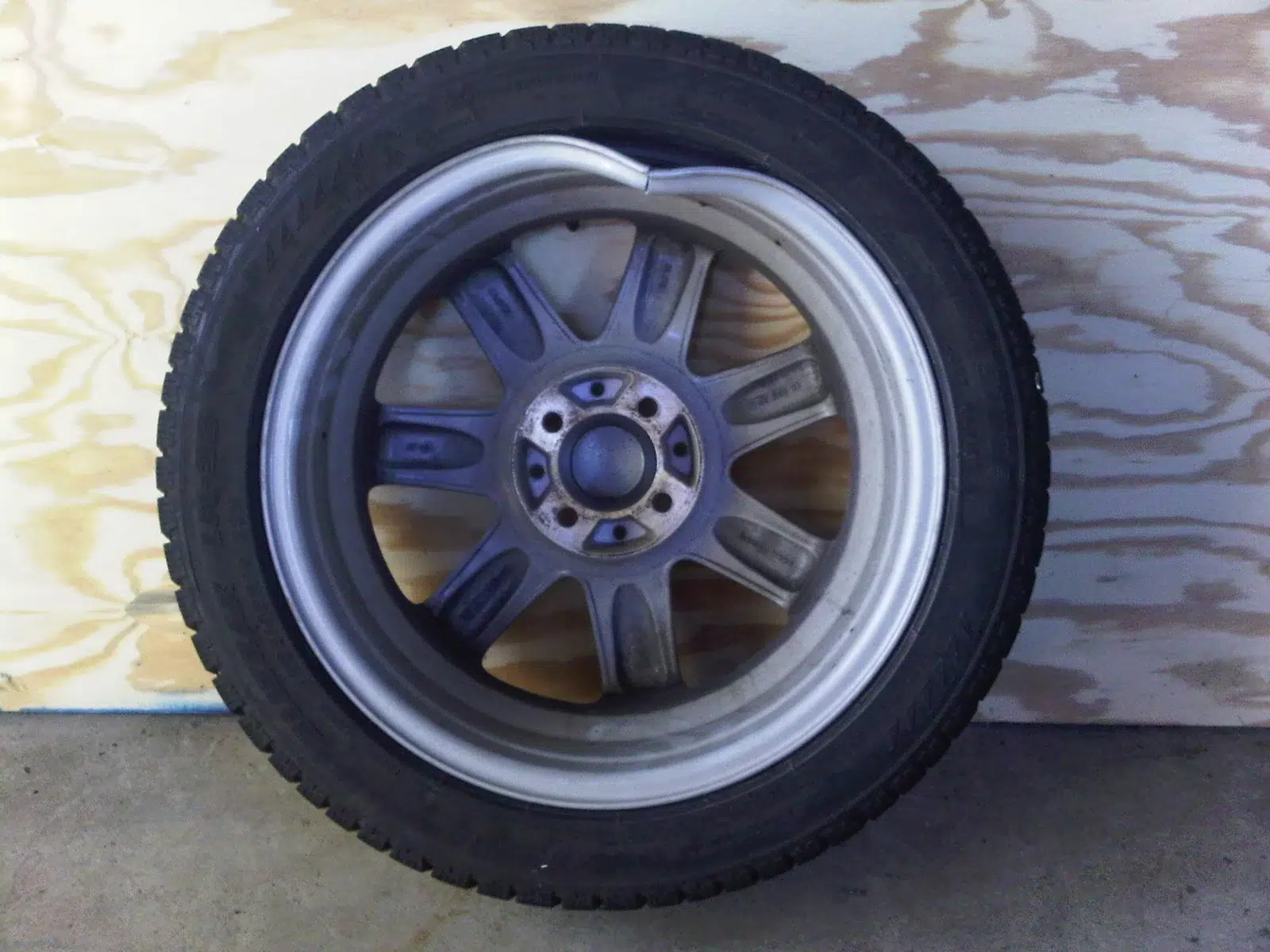 Alloy wheel with a badly bent and cracked rim lip after hitting a pothole, tyre still fitted