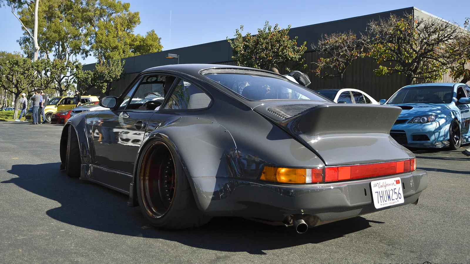 Grey RWB Porsche 930 widebody with bolt-on rear guards, ducktail spoiler and deep-dish wheels at a car meet