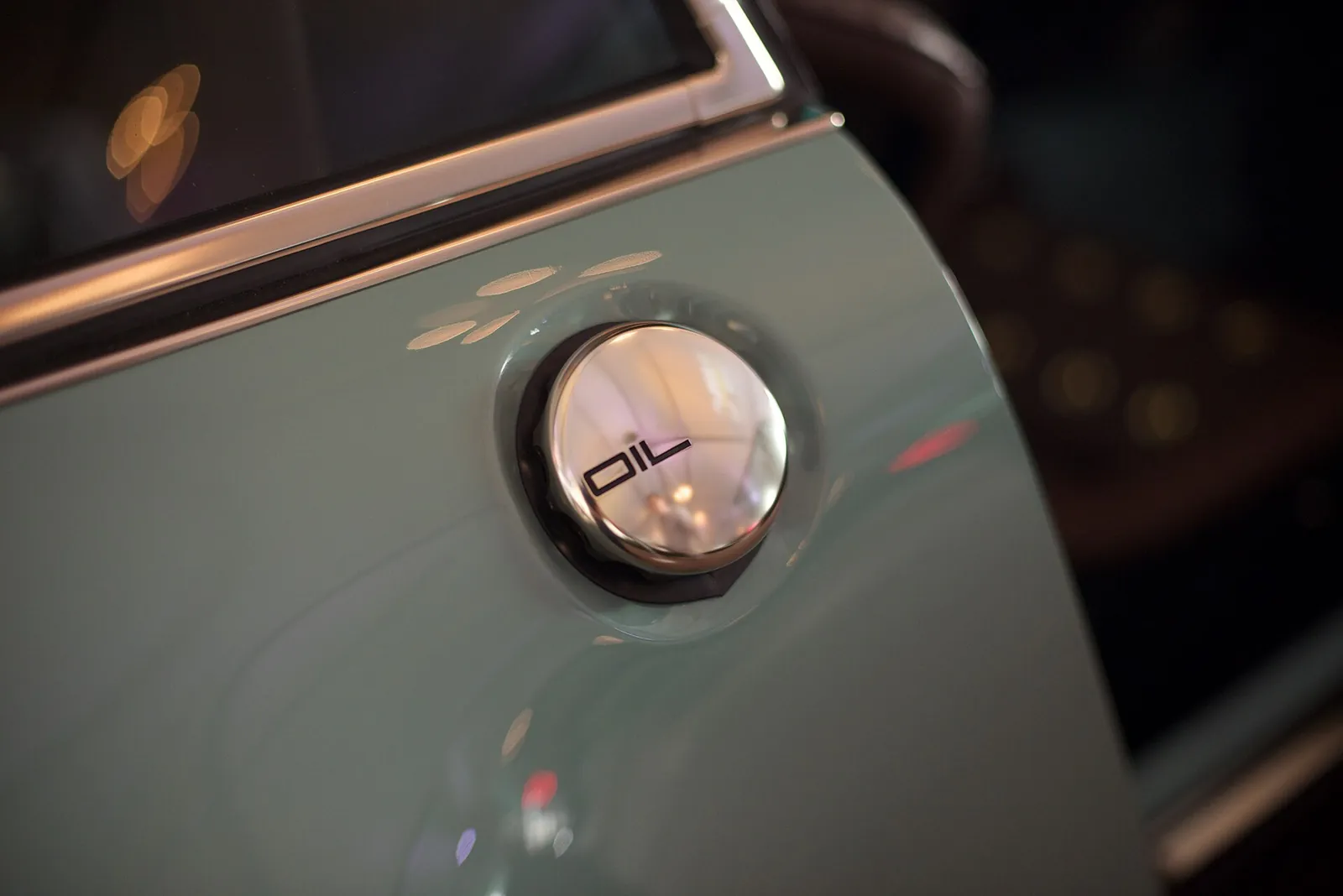 Polished exposed oil filler cap set into the rear quarter panel of a seafoam Singer 911