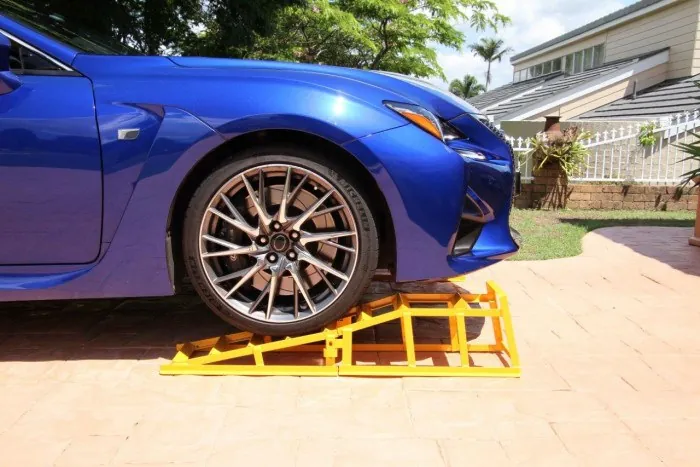 Stanfred CRTP1400 yellow steel low profile car ramps under the front wheel of a blue Lexus coupe on a paved driveway