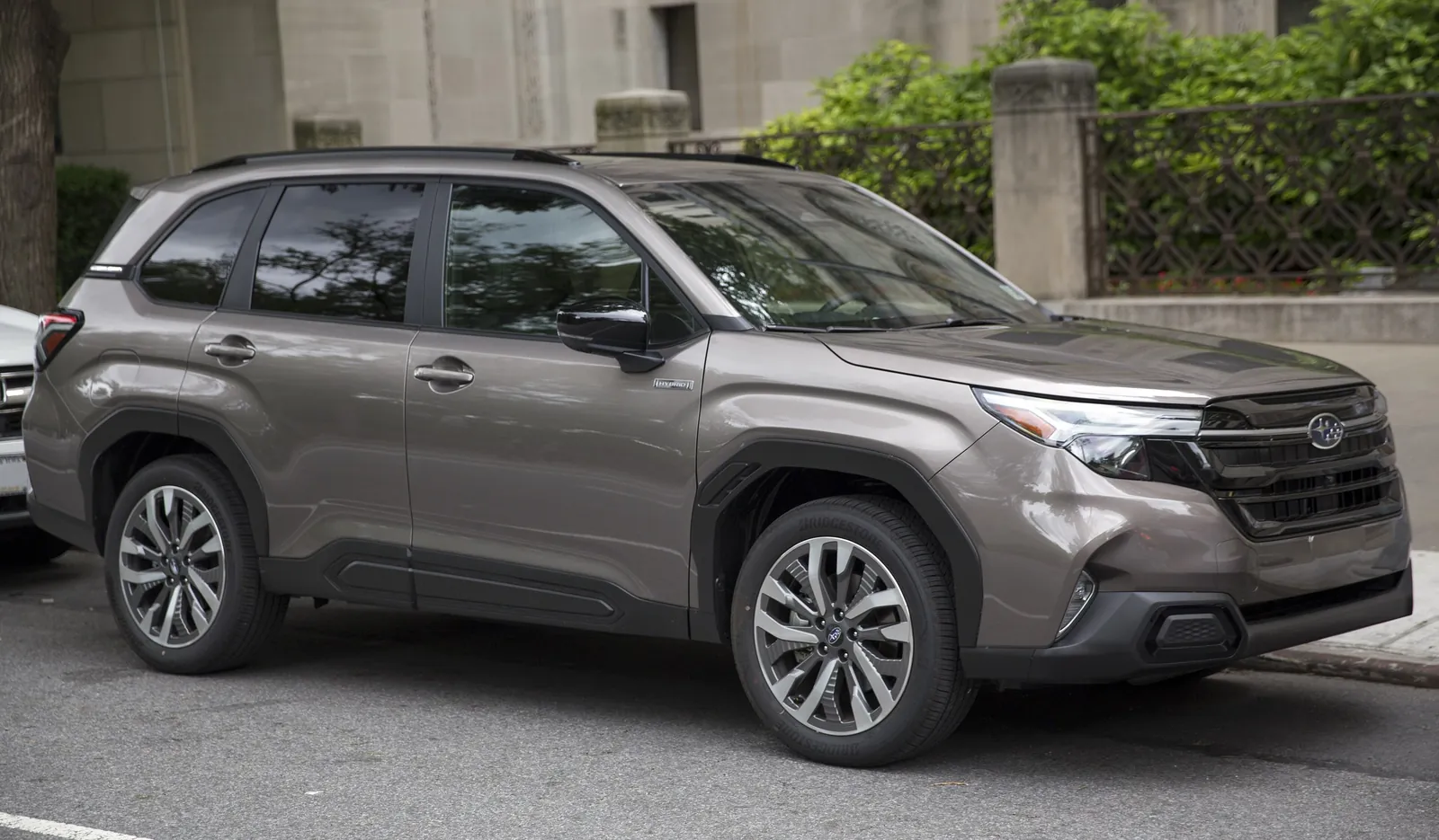 Bronze sixth-generation Subaru Forester Hybrid Touring parked on a street, front three-quarter view