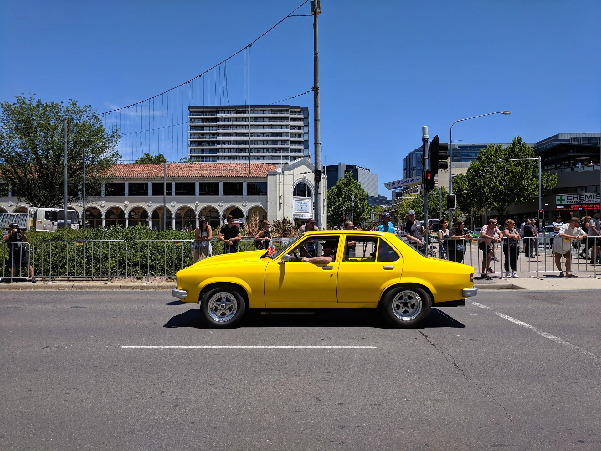 Yellow Holden Torana sedan driving down Northbourne Avenue in Canberra during the Summernats street parade in 2018