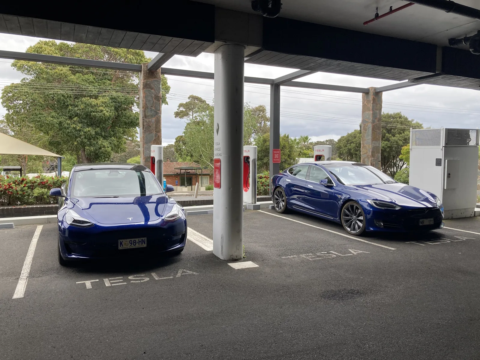 Two Tesla electric cars plugged in under the covered Tesla Supercharger bays at Margaret River, Western Australia