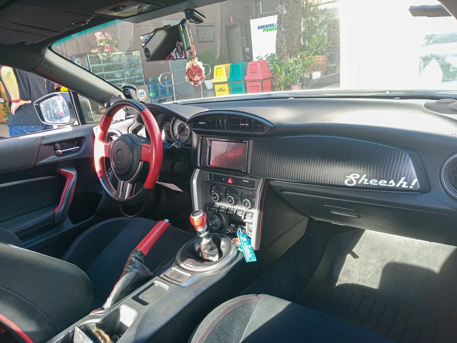 Cabin of a Toyota 86 with six-speed manual shifter and handbrake, fitted with aftermarket red trim pieces