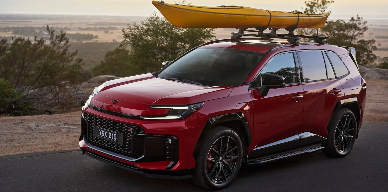 Red 2026 Toyota RAV4 GR Sport with a yellow kayak on the roof racks parked at dusk