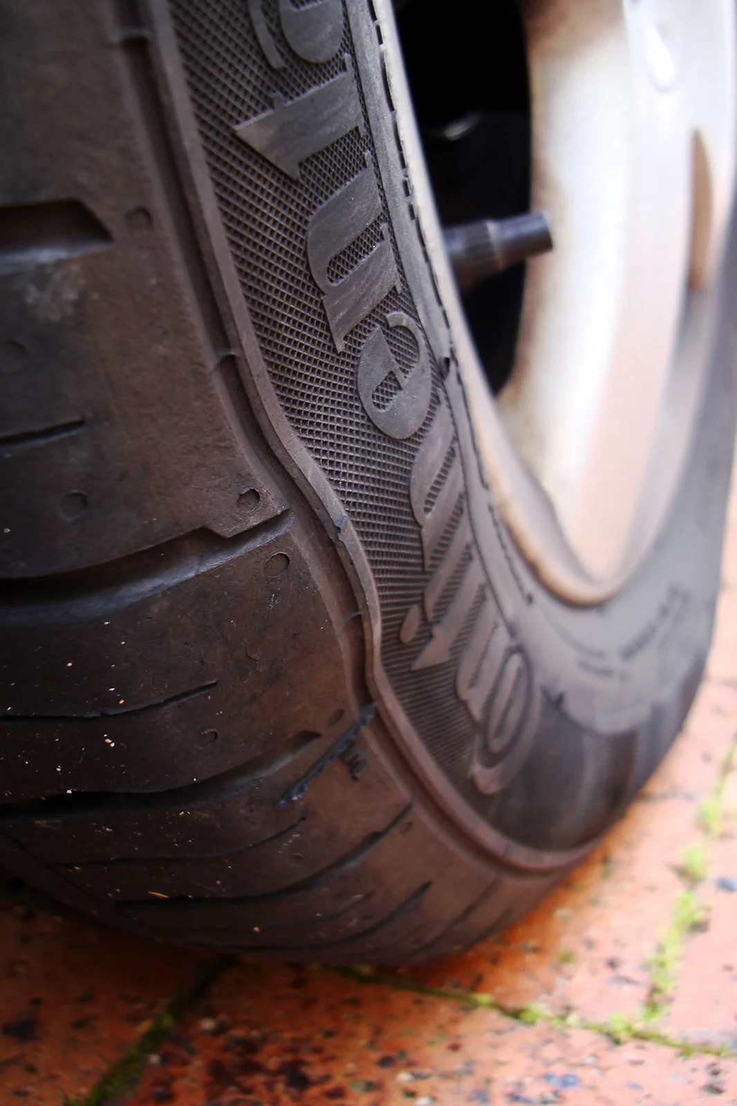 Bulge in a car tyre sidewall caused by an impact with a pothole or speed hump, showing internal damage