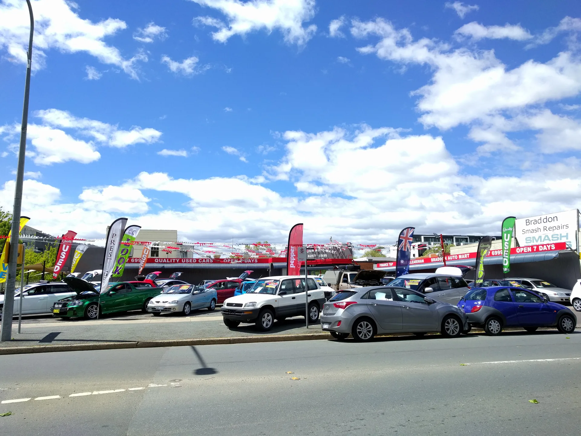 Rows of used cars for sale under bunting at a second-hand car yard in Braddon, Canberra